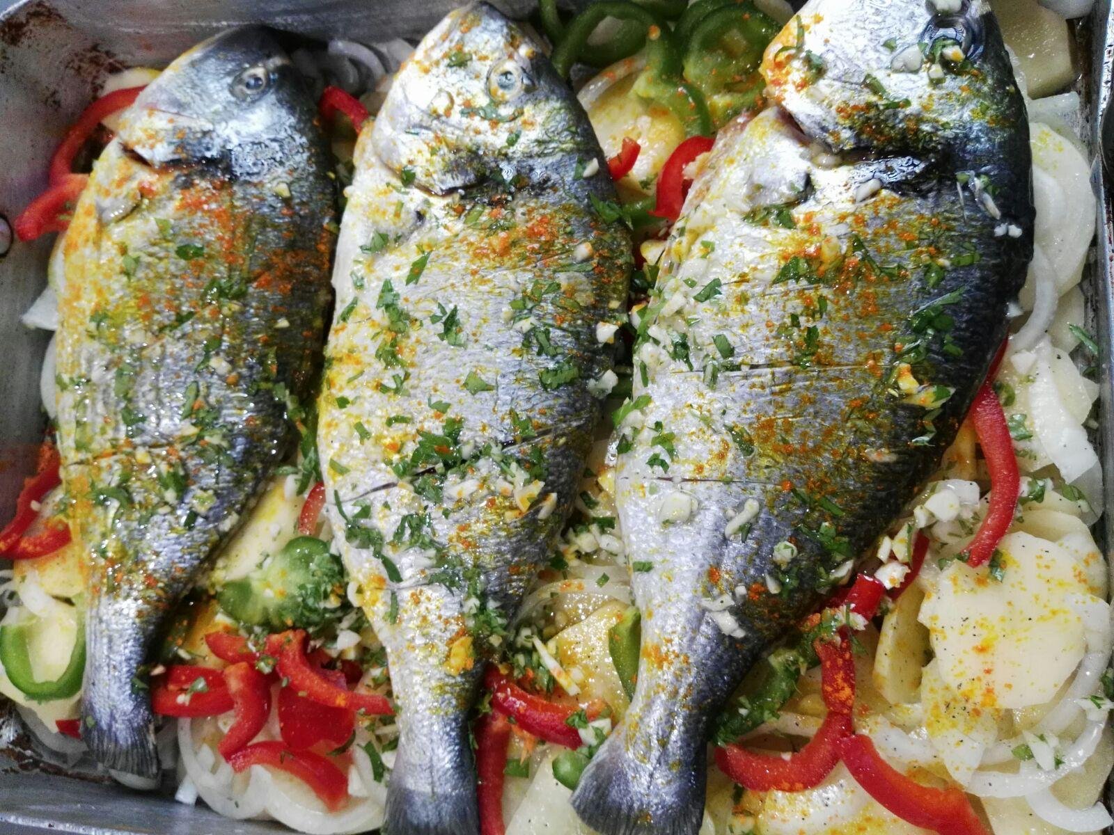Three whole fish dressed with herbs and red peppers, ready for the oven